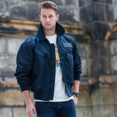 Model wearing Cockpit USA Men's USN Fighter Weapons Nylon Flight Jacket in navy outdoors