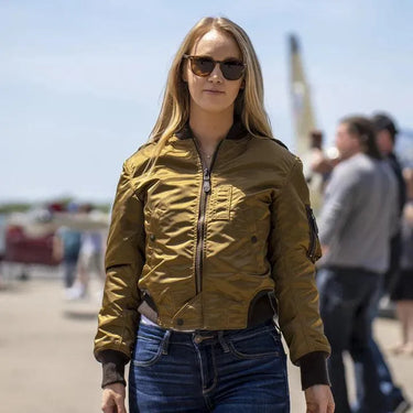 Model wearing the Cockpit USA Jenny MA-1 Nylon Flight Jacket outdoors at an aviation event.