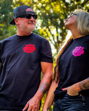 Man and woman wearing Legendary Color Shield Motorcycle T-Shirts outdoors, showcasing fit and red/pink logo, Made in USA