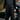 Person wearing black leather overalls helmet standing next to a motorcycle