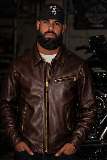 Man wearing a brown leather jacket and cap in a motorcycle-themed setting