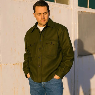 Model wearing olive CPO shirt outdoors with aircraft in background