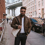 Man wearing Mustang Vintage A-2 jacket on city street with sunglasses and tote bag