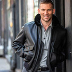 Male model wearing Cockpit USA Men's Submariner G-1 black leather flight jacket outdoors in urban setting