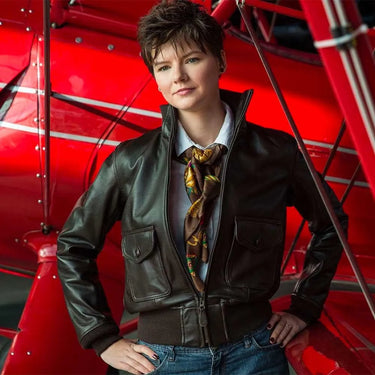 Woman posing in Cockpit USA Women's Amelia leather jacket in front of red vintage aircraft