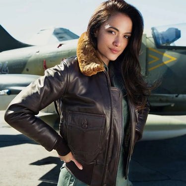 Female model wearing the Cockpit USA Women’s G-1 Flight Jacket beside a vintage military aircraft