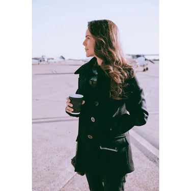 Model wearing the Cockpit USA Women's Navy Peacoat outdoors with coffee and sunglasses.