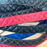 Assorted diamond-stitched leather belts in red, black, blue, and yellow, laid flat for detail view, Made in USA