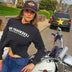 Woman wearing Legendary USA Booty Call cropped hoodie, front view with logo text, standing beside classic motorcycle