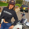 Woman wearing Legendary USA Booty Call cropped hoodie, front view with logo text, standing beside classic motorcycle