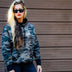 Female model standing wearing Legendary Sniper camo hoodie, showing fit and casual motorcycle style