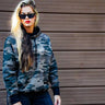 Female model standing wearing Legendary Sniper camo hoodie, showing fit and casual motorcycle style