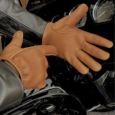 Rider wearing tan deerskin gloves from Legendary USA while gripping motorcycle handlebars, showcasing fit and durability